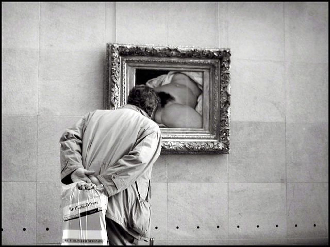 Un visiteur de dos observe un tableau dans un cadre doré